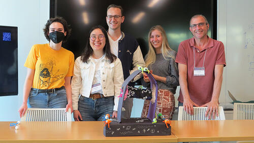 6 people standing with a crafted sculpture in front of them.