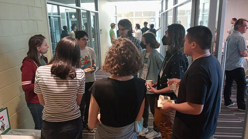 people standing in a hallway in a circle talking.