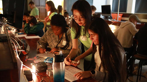 people working at a lab table with a light shining from the table.