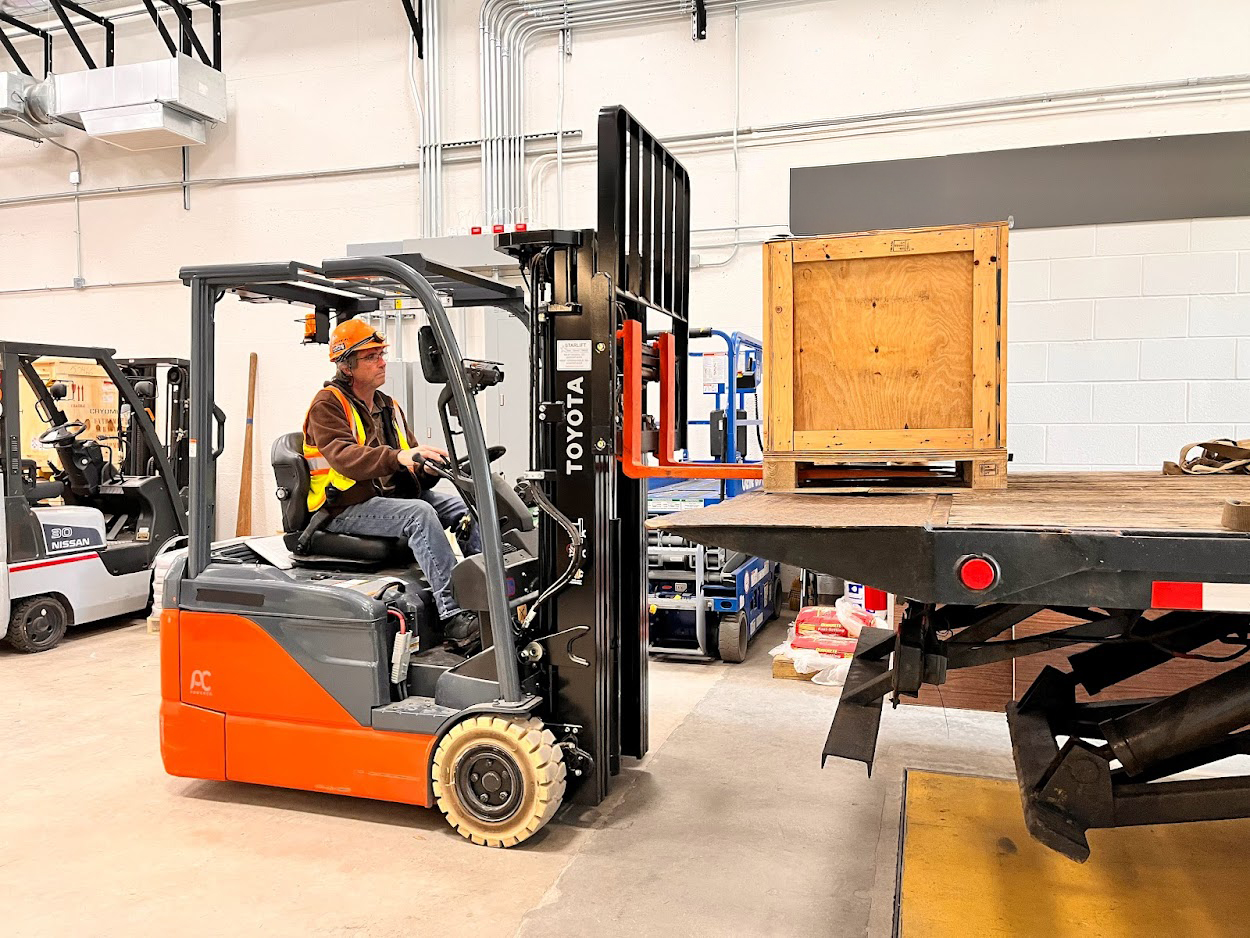 Person using a forklift to lift a box onto a truck at Wright Lab.
