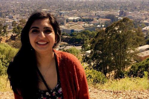 Headshot of person with scenic overlook background of some buildings and trees.