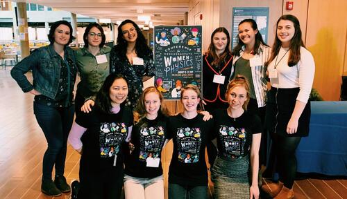 10 people standing in front of a sign that says women in physics.