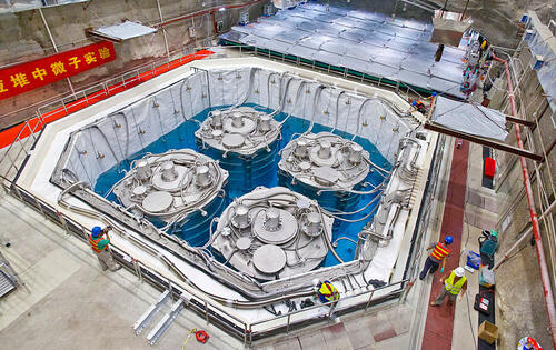 Picture of scientific equipment with people in hard hats and vests standing by it.