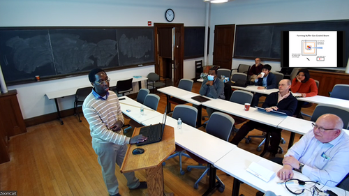 person giving talk in a classroom with an audience.