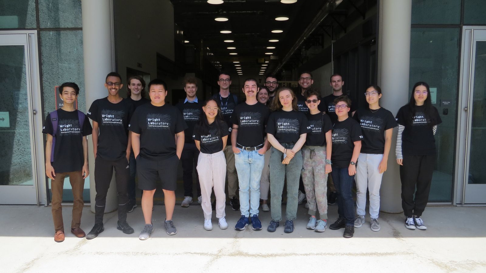 large group of people posing in front of a building with black Wright Lab T-shirts on.