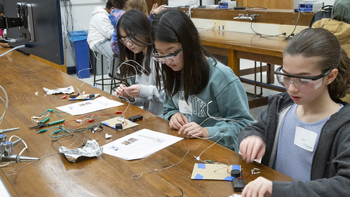 three students with goggles workign on circuitry at a table