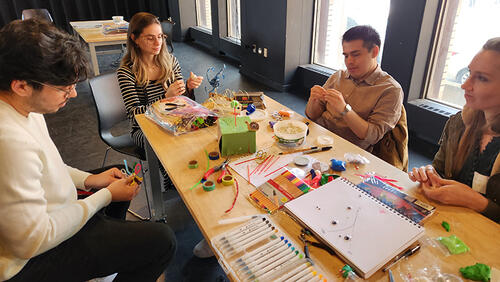 group of people working at table with art supplies.