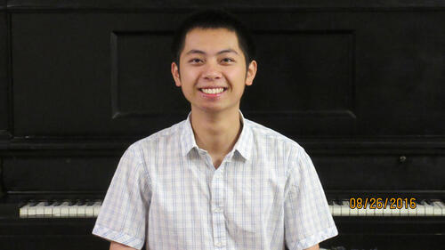 person head and shoulders in front of a piano.