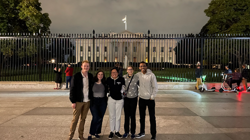 group of five people standing in front of the White House.