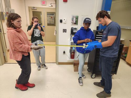 people standing at a group with a measuring tape extended.