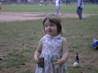 child eating M&amp;Ms at a baseball field.