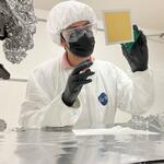 person in clean room garb working on instrumentation