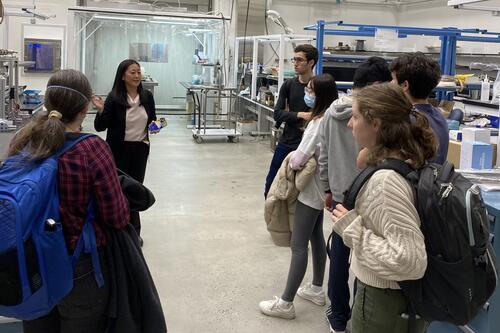 people standing in a lab looking at another person talking.