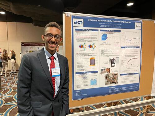 person standing next to conference poster on bulletin board.