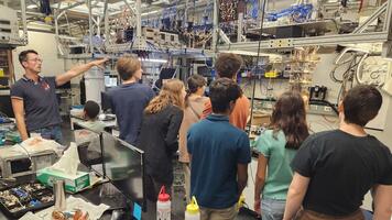 Group of people taking a tour of a lab with lots of wires and equipment.