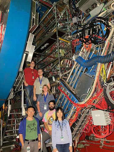 6 people standing in front of a large machine with lots of wires.