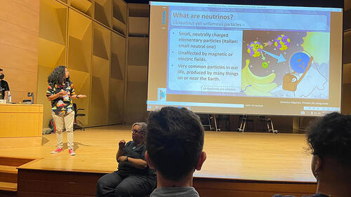 person giving talk in front of large screen with presentation on it.