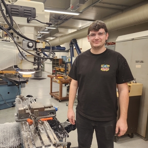 Dylan standing next to a machine in the shop.