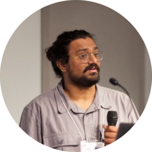 Pranav Sanghavi holding a microphone in front of a podium with another microphone.