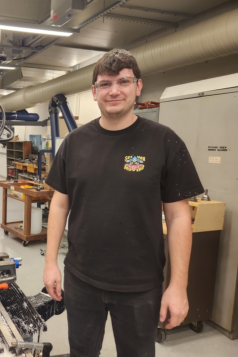 Dylan standing next to a machine in the shop.