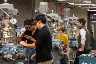 Four people working at milling machines at Wright Lab.