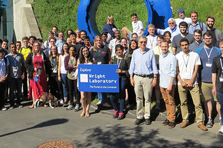 large group of NNPSS 2018 students and faculty posing by large, blue circular Portal sculpture outside of Wright Lab.