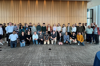 large group of people standing in front of a wall, posting.