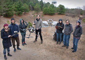 group of people standing with drone in front of radio telescope