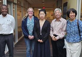 5 people posing for picture in a line facing viewer.