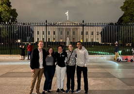 group of five people standing in front of the White House.