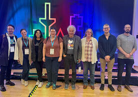 8 Wright Lab Relativistic Heavy Ion group members standing in front of Quark Matter 2025 logo.