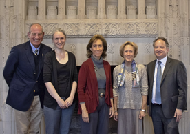 Group of 5 people standing in front of wall; see caption for more details.
