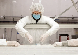 people working in a clean room in lab gear.