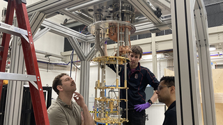 Three people installing a dilution fridge for the ALPHA experiment at Wright Lab.
