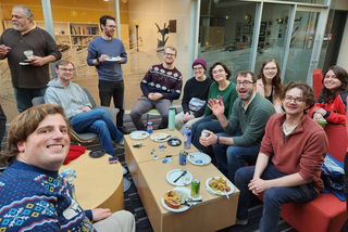 Group of people smiling sitting down at Wright Lab winter celebration.
