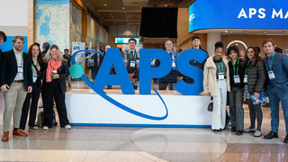 People posing in front of APS logo