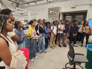 Group of people standing in a large Wright Lab lab facility listening.