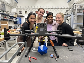 Four Laura Newburgh students and postgraduate associate standing behind drone and smiling.