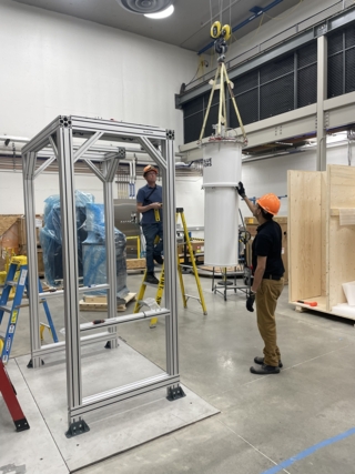 Two people in hard hats installing the ALPHA dilution fridge at Wright Lab.