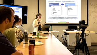 Barbara Cruvinel Santiago giving Kimball Smith Lecture at Wright Lab with audience members in foreground.