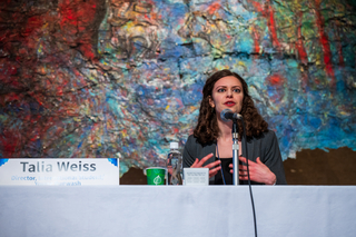 Wright Lab graduate student Talia Weiss at panel table with name card at conference.