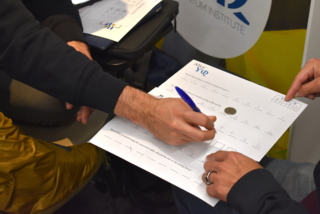 People's hands filling out a form with a pen.