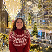 Person in foreground with decorated background of lights and trees.