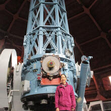 Person standing in front of large telescope structure.