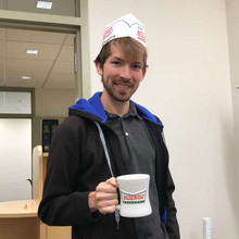 person holding mug and wearing paper hatt