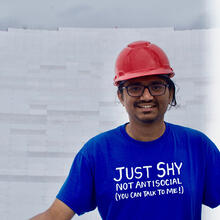 Close up of person in a hardhat standing in a radio telescope dish.