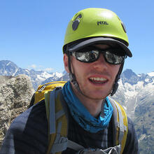 headshot of person in front of mountain range.