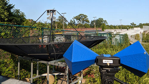radio telescope equipment on flat roof of building with vegetation surrounding it.