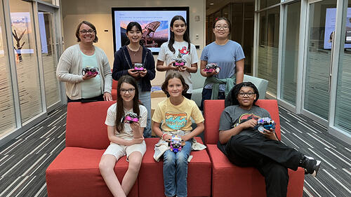 7 people posing holding robots and smiling.