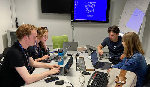 4 people sitting around a table with computers.